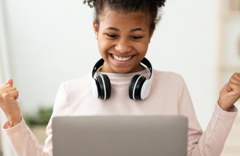 Little Winner. Excited Black Girl At Laptop Gesturing Yes Getting A-Grade During Webinar At Home. Online School Tests Concept