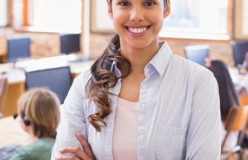 Pretty teacher smiling at camera at back of classroom