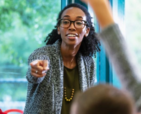 A dedicated black female teacher enthusiastically guiding her students through a lesson, fostering an engaging and inclusive learning environment.