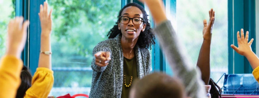 A dedicated black female teacher enthusiastically guiding her students through a lesson, fostering an engaging and inclusive learning environment.