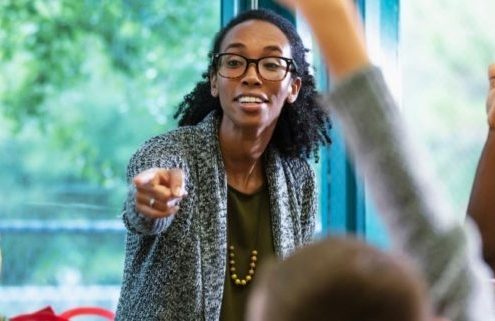 A dedicated black female teacher enthusiastically guiding her students through a lesson, fostering an engaging and inclusive learning environment.