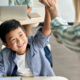 Young male student of Asian heritage smiles as he high-fives his academic coach standing in front of him.