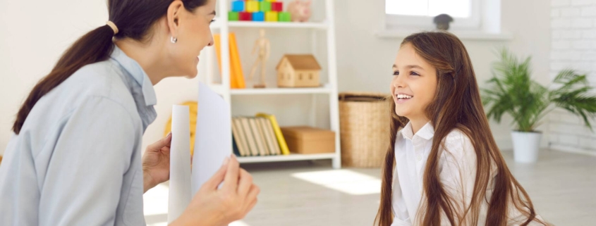 ADHD coach sits in front of an elementary age girl holding up a flashcard as they practice learning techniques.