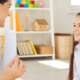 ADHD coach sits in front of an elementary age girl holding up a flashcard as they practice learning techniques.